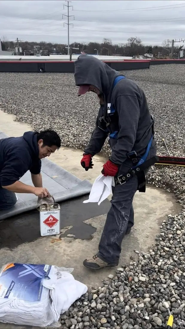 Two roofers working on a flat roof with a gravel surface