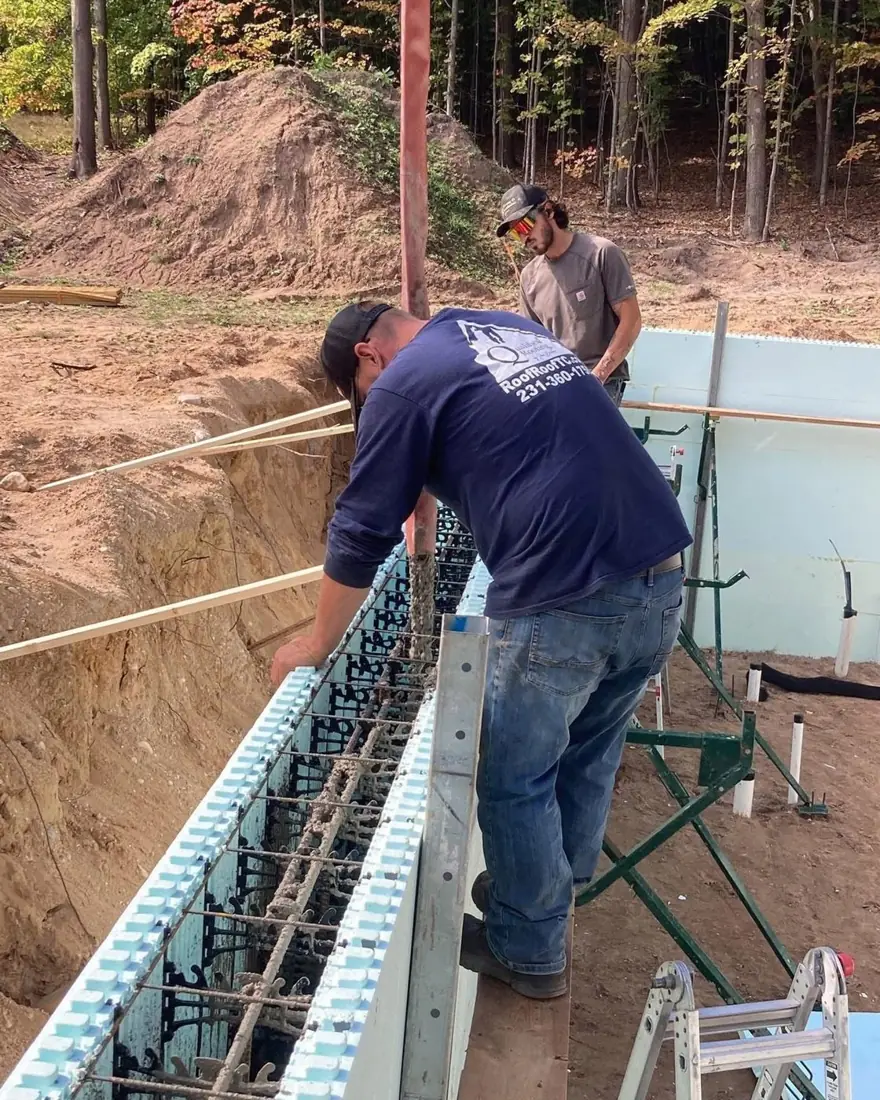 Worker setting rebar in an insulated concrete foundation wall