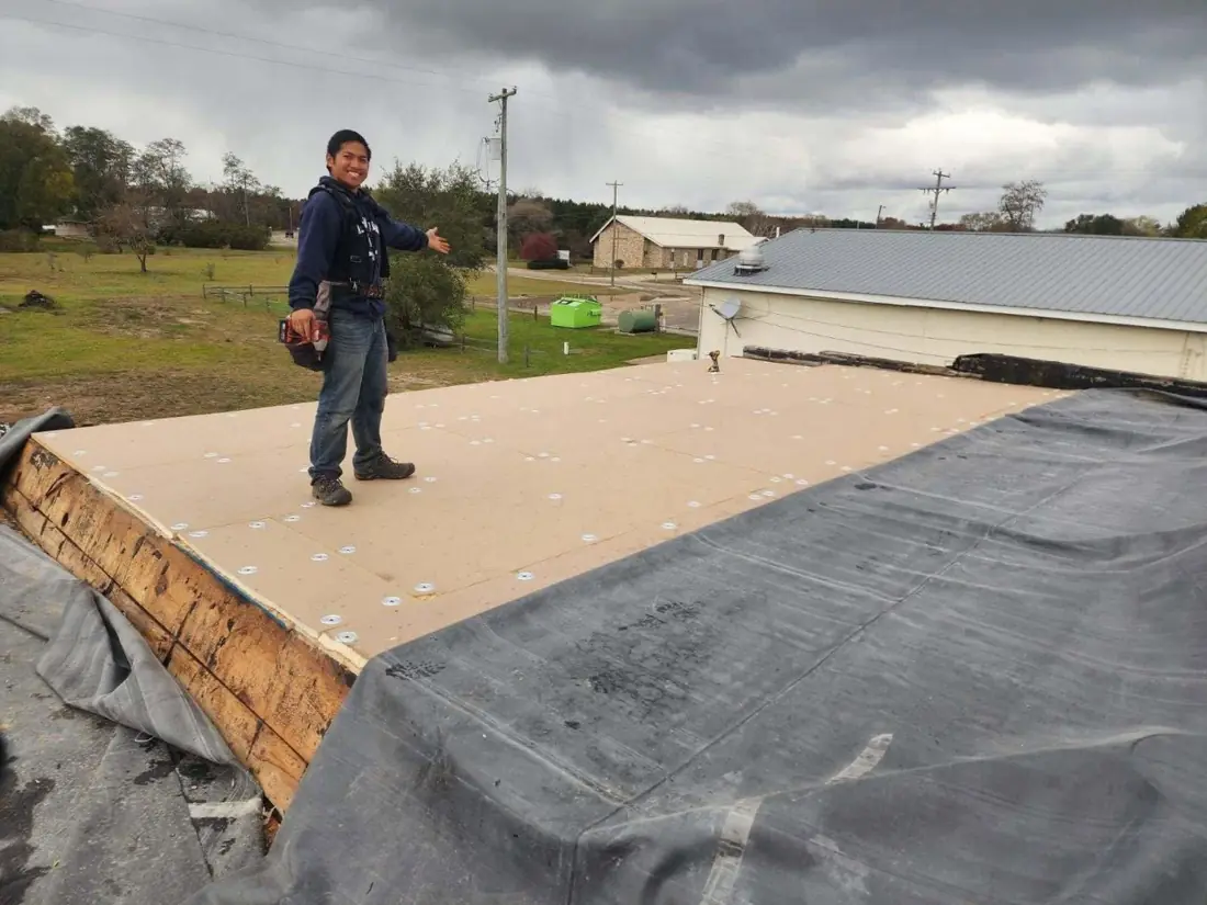 Crew member on a flat commercial roof deck with membrane laid out