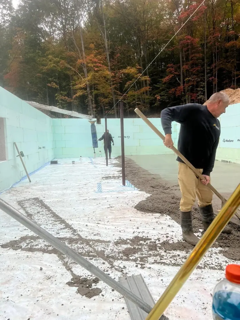 Worker leveling a foundation slab inside insulated concrete walls